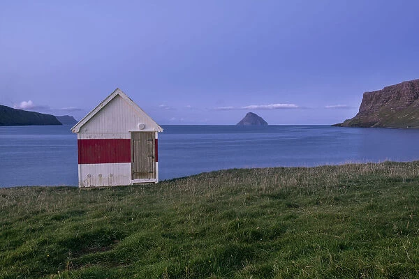 Blue hour at a small wooden house by the sea on Suduroy, Faroe Islands, Denmark, Europe