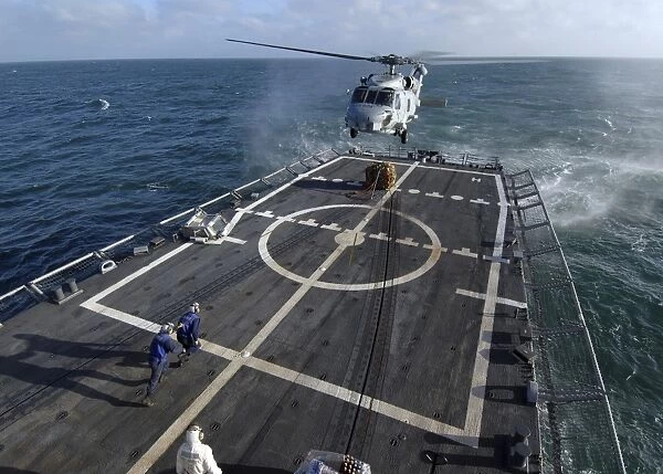 U. S. Navy sailors prepare to attach a pallet of supplies to an SH-60B Seahawk helicopter