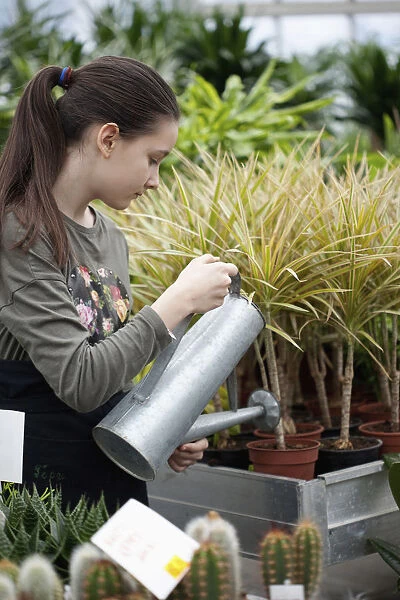 Young girl working in garden centre, Watering plants