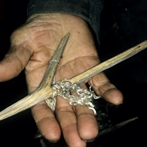 Wooden fishing hook on palm of a Siberian shaman /