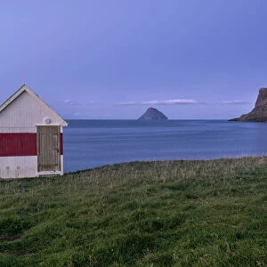 Blue hour at a small wooden house by the sea on Suduroy, Faroe Islands, Denmark, Europe