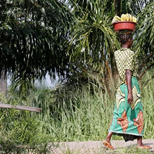 An internally displaced Congolese woman carries a basin containing bananas as she walks