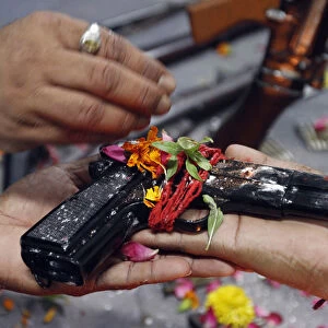 Police officers hold a 9mm pistol as they offer prayers in front of weapons