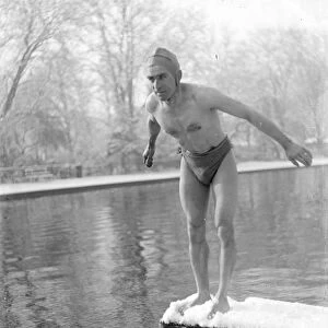 Winter swimming. A man diveing into the cold water. He is standing on a snow-covered