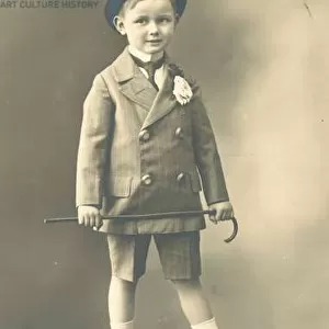 Boy in double-breasted suit, wearing a top hat and holding a cane (b / w photo)