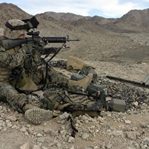 A Marine rifleman provides security for machine gunners atop a hill