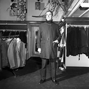 Male model wearing raincoat in menswear department. 1966